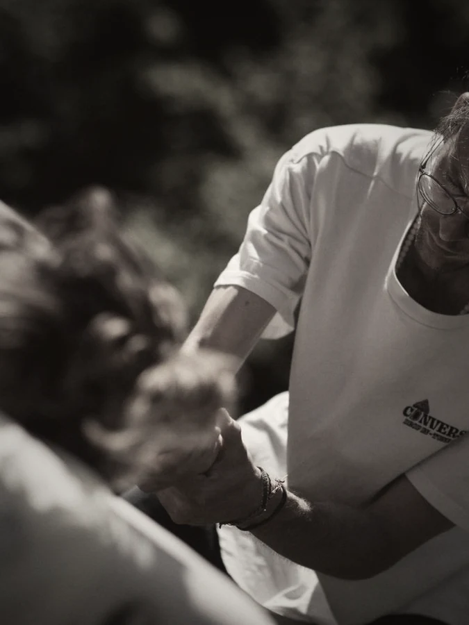 Marco Krastev working, hands on a guest's arm during an outdoor massage session.